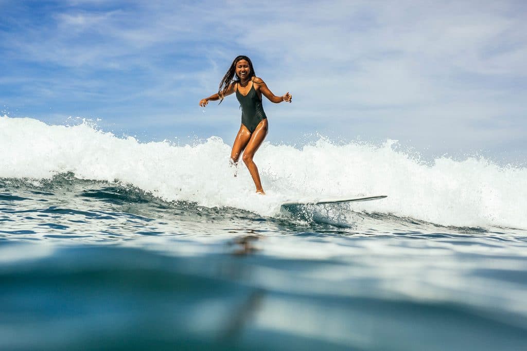 Female surfer in black swimsuit riding the whitewater