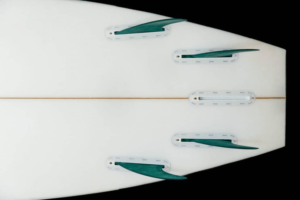 Close-up of 5-fin surfboard tail with 4 green fins installed