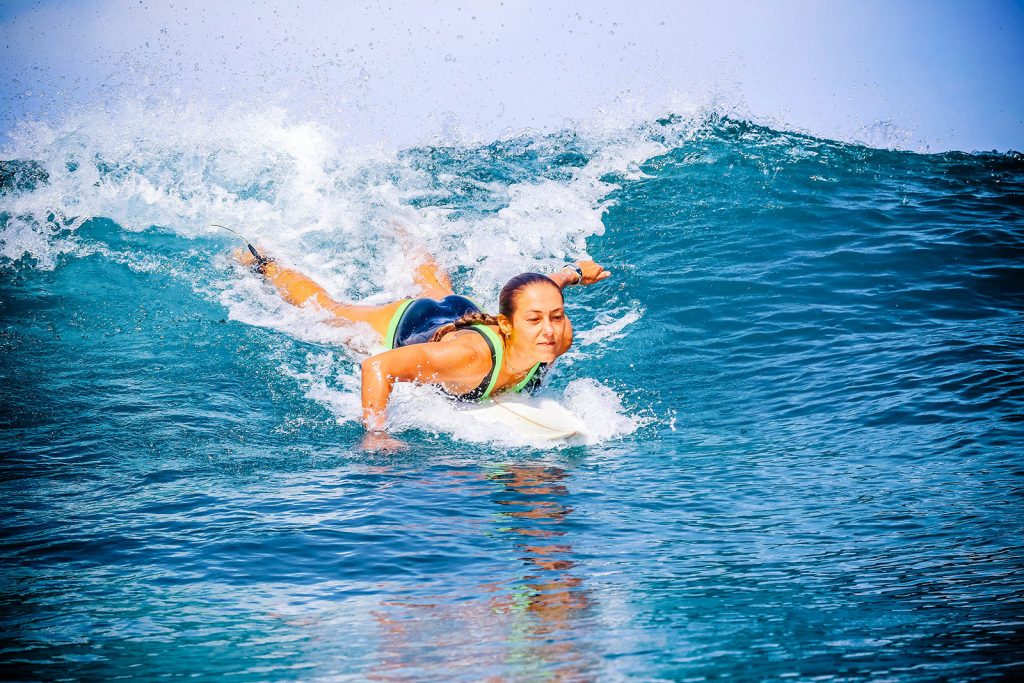 Female surfer paddling for a wave