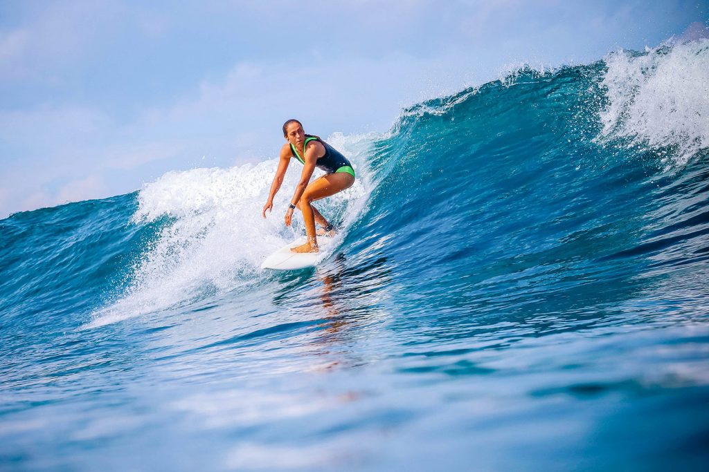 Female surfer popping up on a wave